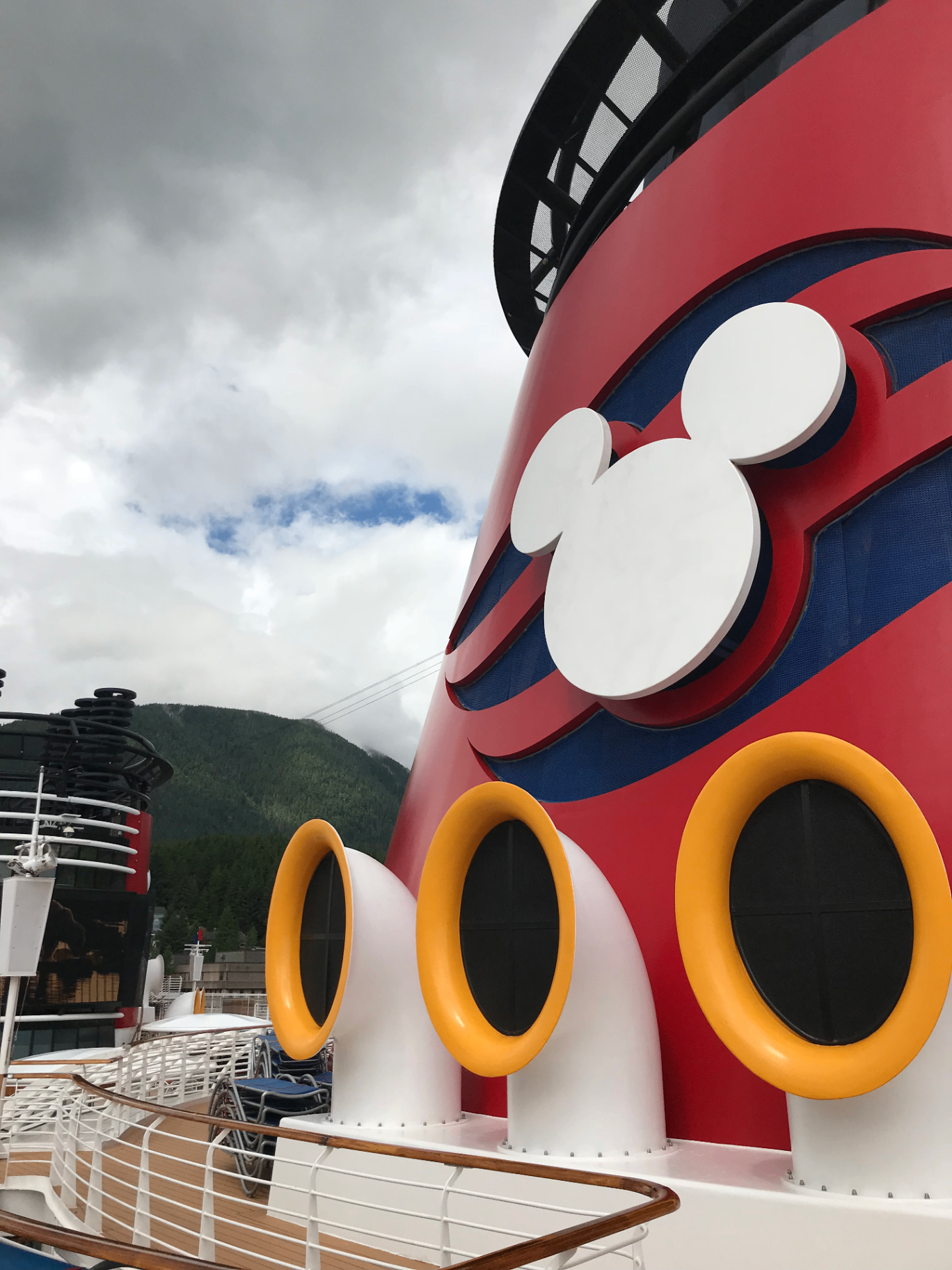 Close-up of a Disney Cruise ship funnel against coastal mountains